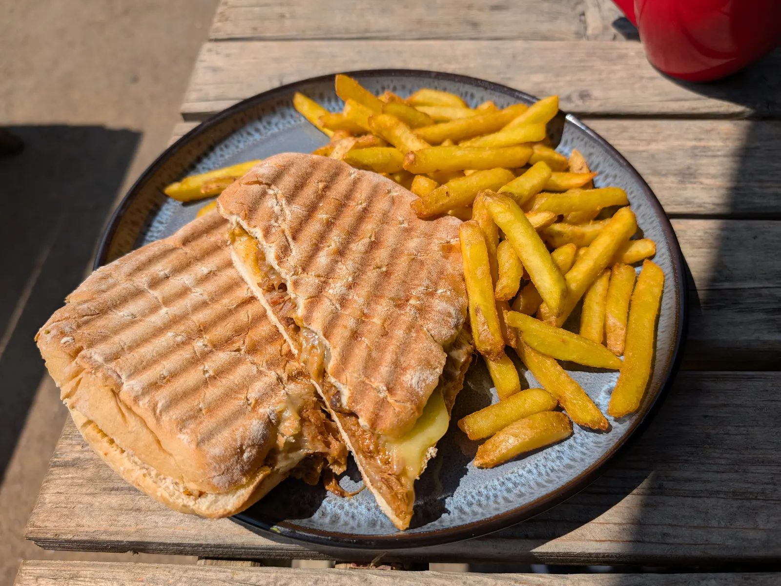A pressed sandwich of shredded meat and melted cheese, with fries