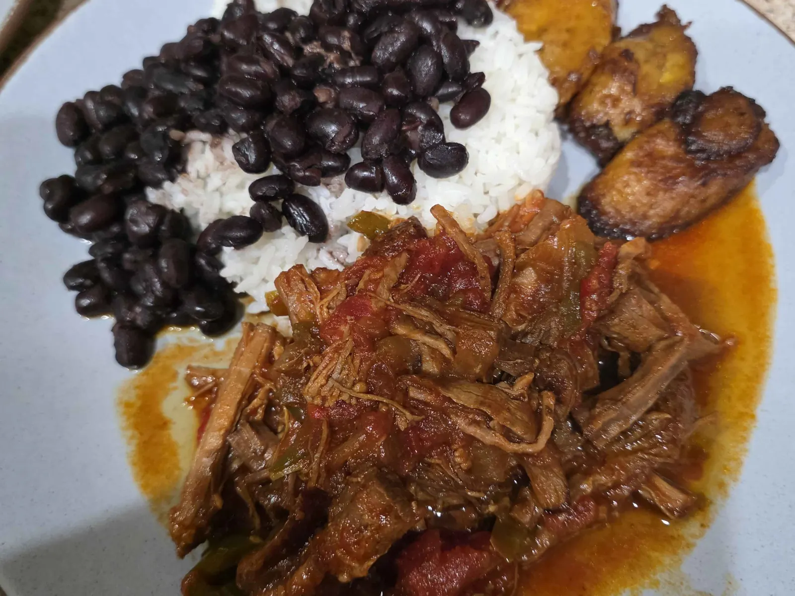 Shredded beef in tomato sauce with white rice, black beans and sweet plantains